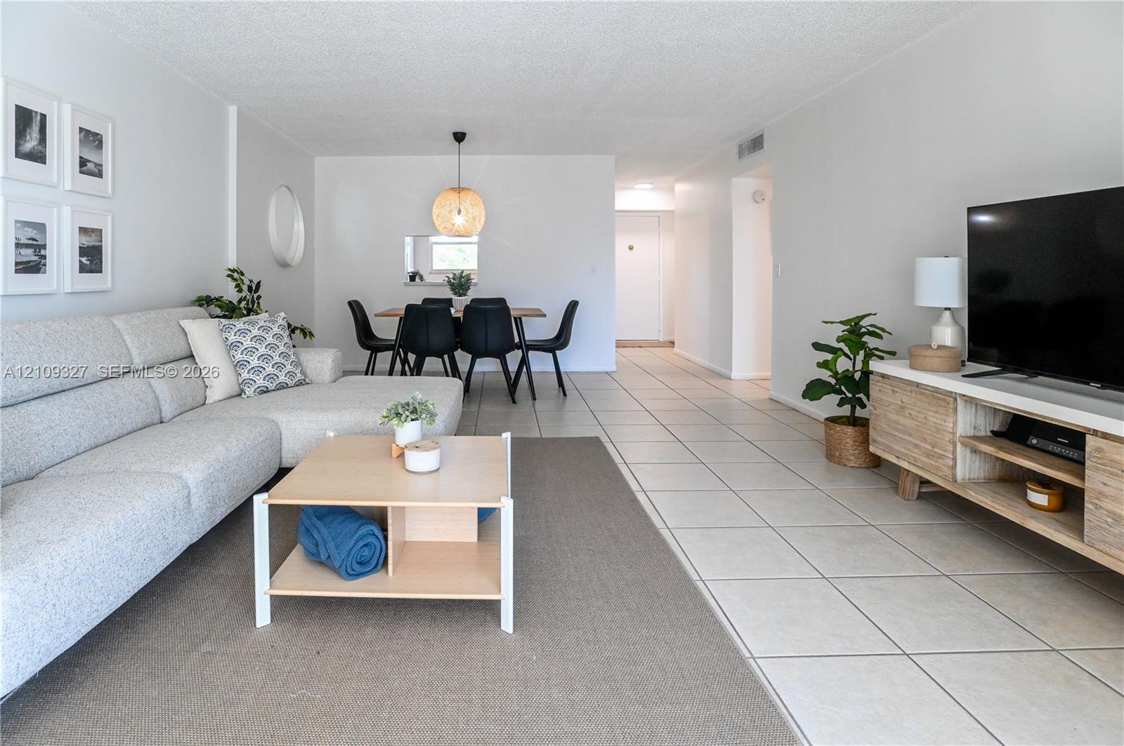Large-format ceramic tile flooring throughout, spherical woven pendant light fixture, and pass-through window opening