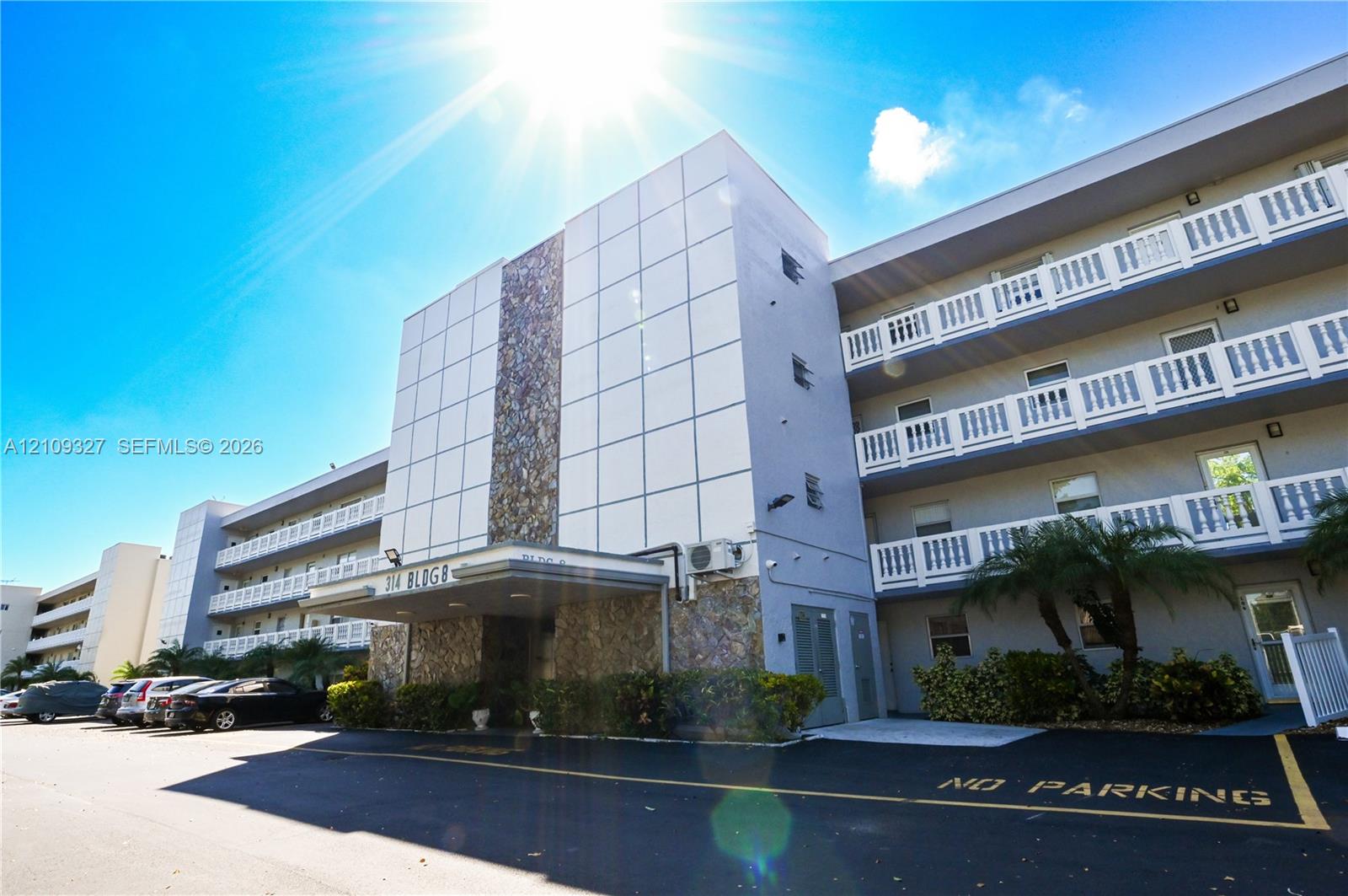 Multi-story residential building exterior featuring stacked balconies, stone-accented facade, and a covered ground-level entryway