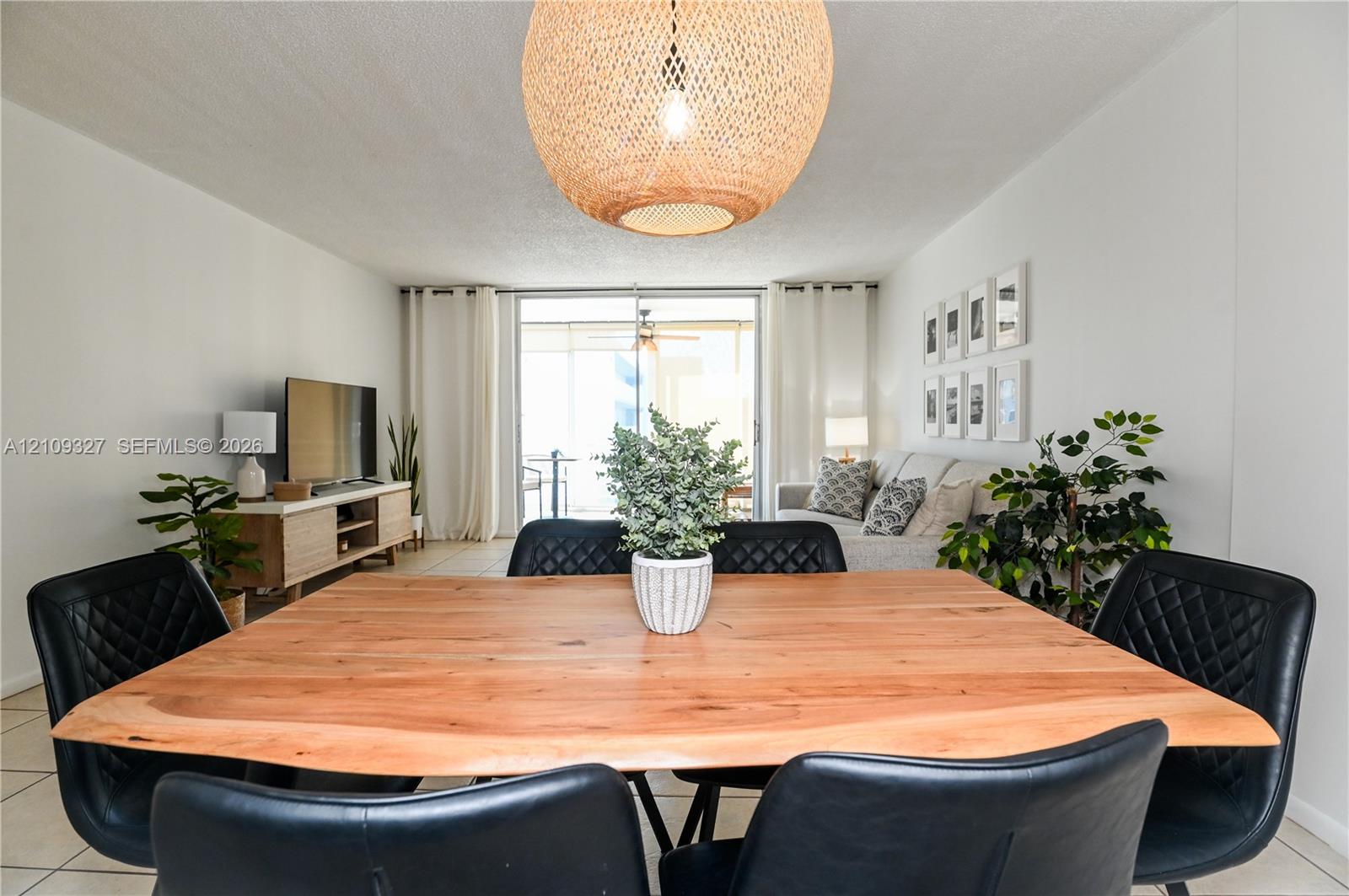 Large woven dome light fixture, sliding glass doors, and neutral tile flooring
