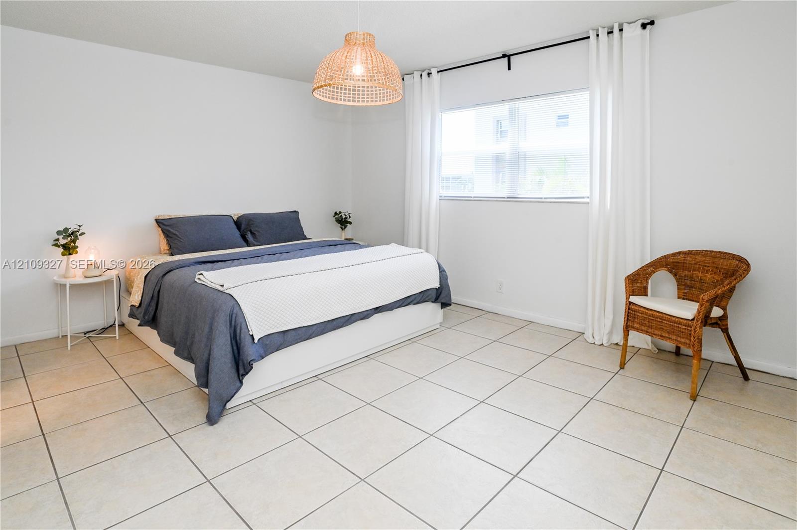Neutral-toned ceramic tile flooring, woven basket-style pendant lighting, and a window with curtains