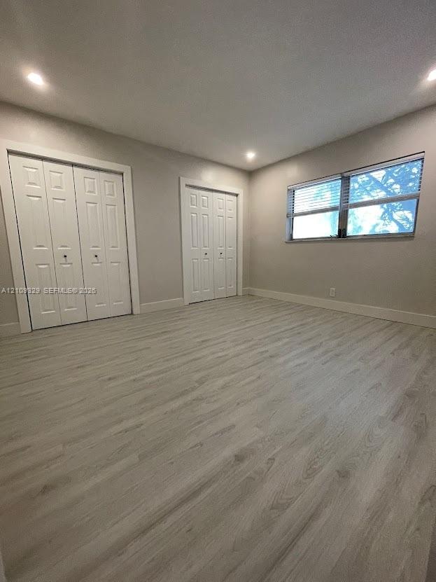 Light-filled interior featuring wood-finish flooring, recessed lighting, and two double-door closets