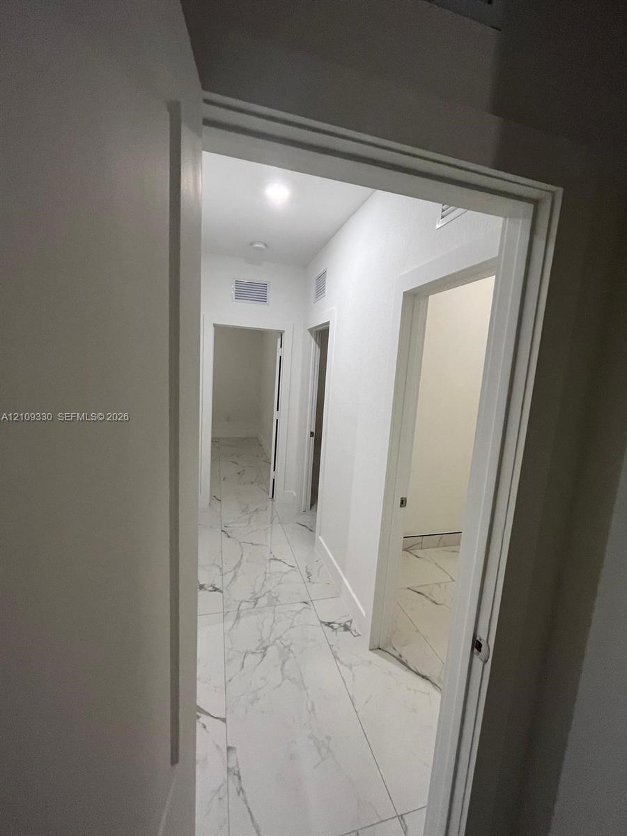 Hallway featuring large-format tile flooring with veining detail, recessed lighting, and white door frames
