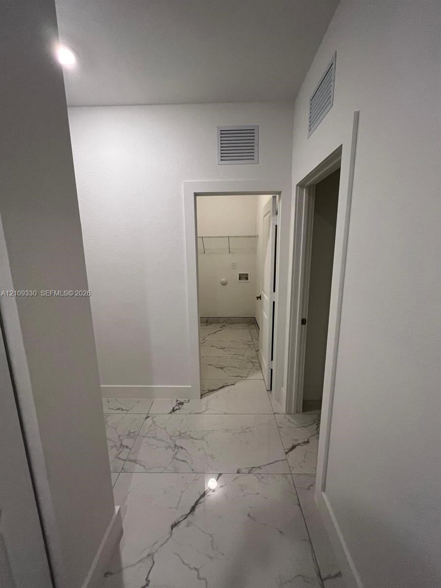 Large-format rectified tile flooring with a veined pattern, neutral wall palette, and walk-in storage area featuring wire shelving