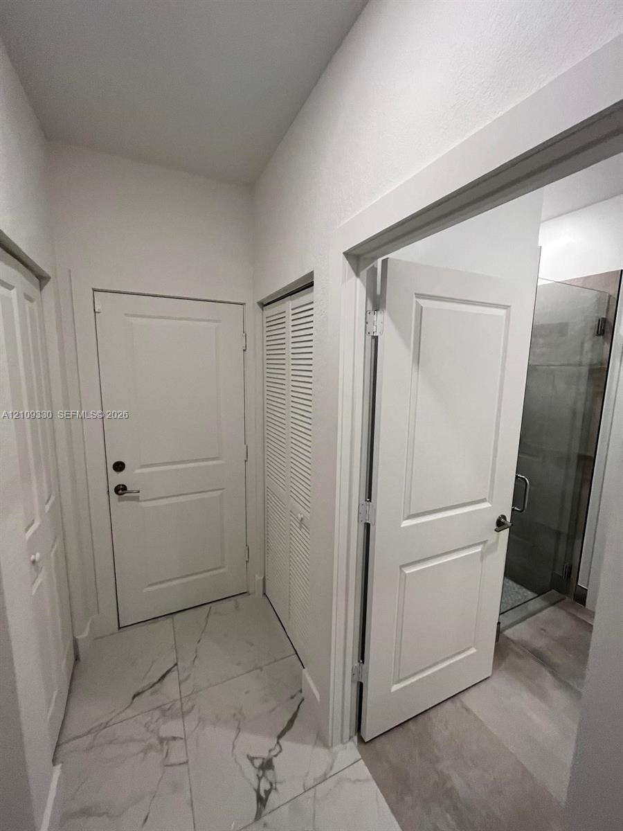 Large-format stone-style tile flooring, solid core two-panel interior doors, and a double-door louvered closet
