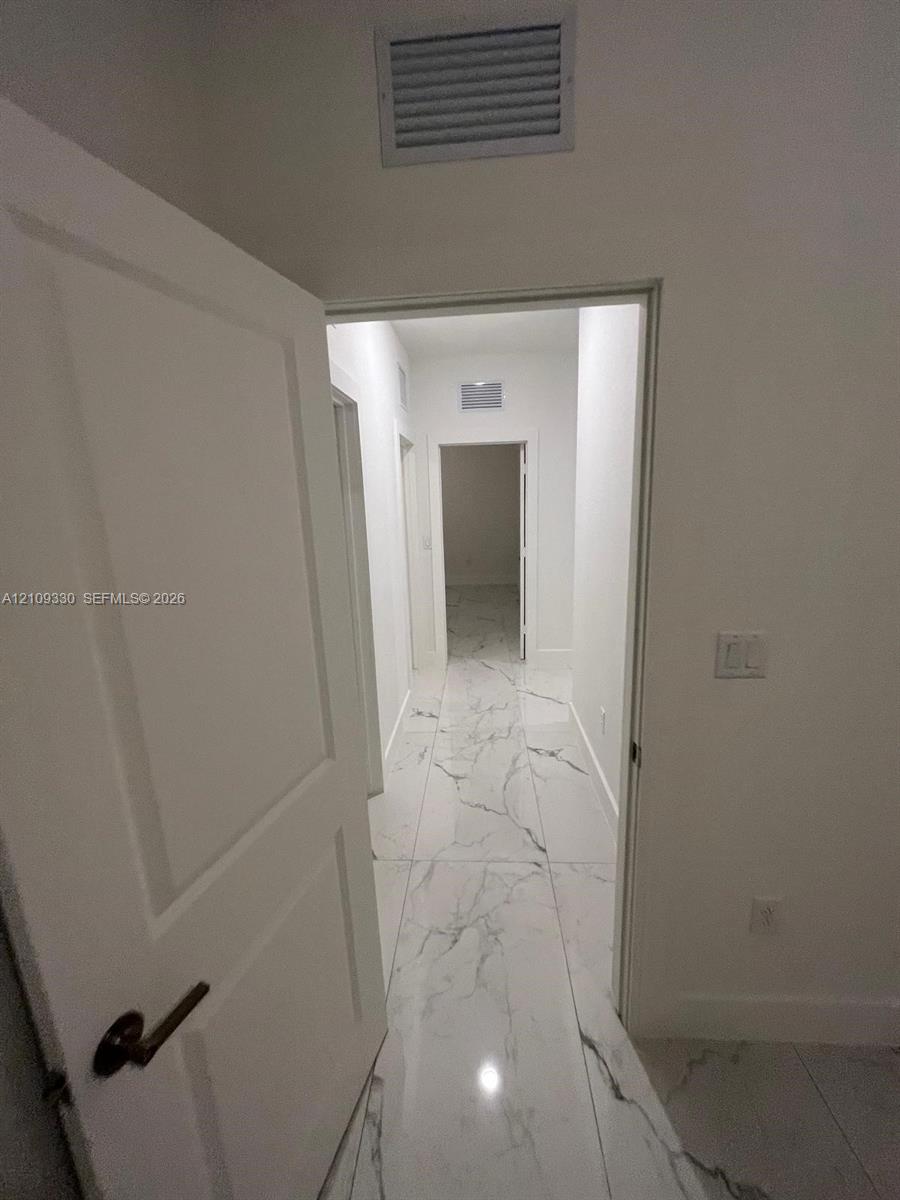 Large-format porcelain tile flooring with veined detailing and clean white wall finishes