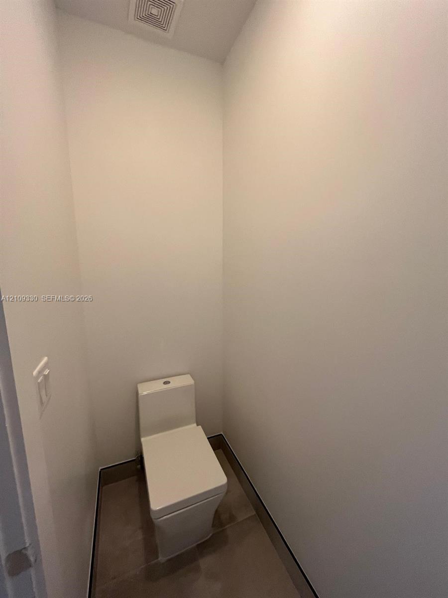 Minimalist room featuring large-format tile flooring and a sleek, one-piece dual-flush toilet