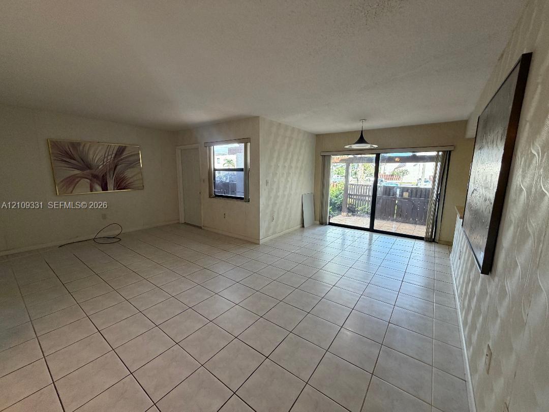 Neutral-toned interior featuring ceramic tile flooring, textured wall accents, a pendant light fixture, and sliding glass doors with exterior access