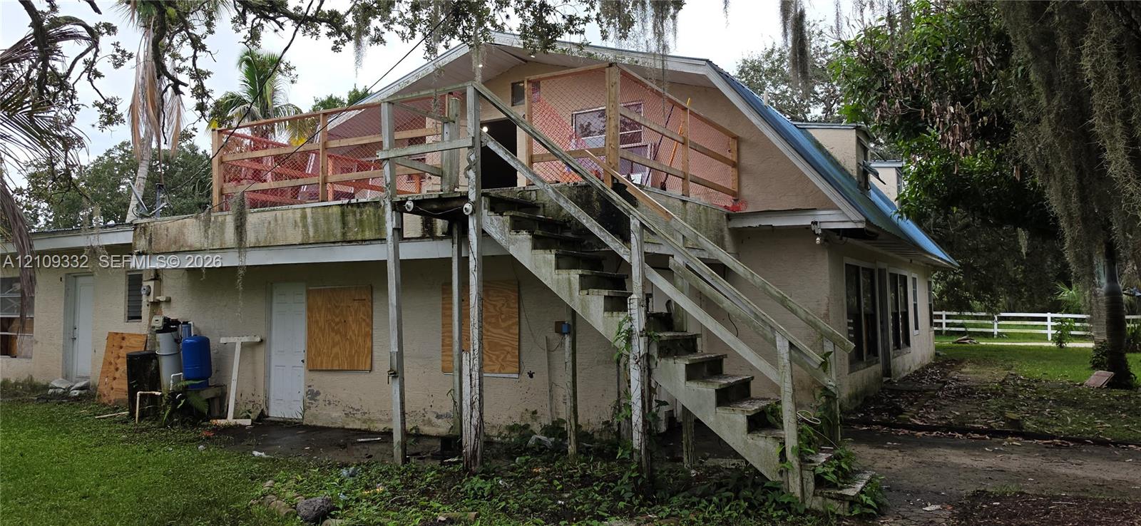 Stucco exterior featuring an elevated wooden deck with external staircase and a pitched roofline