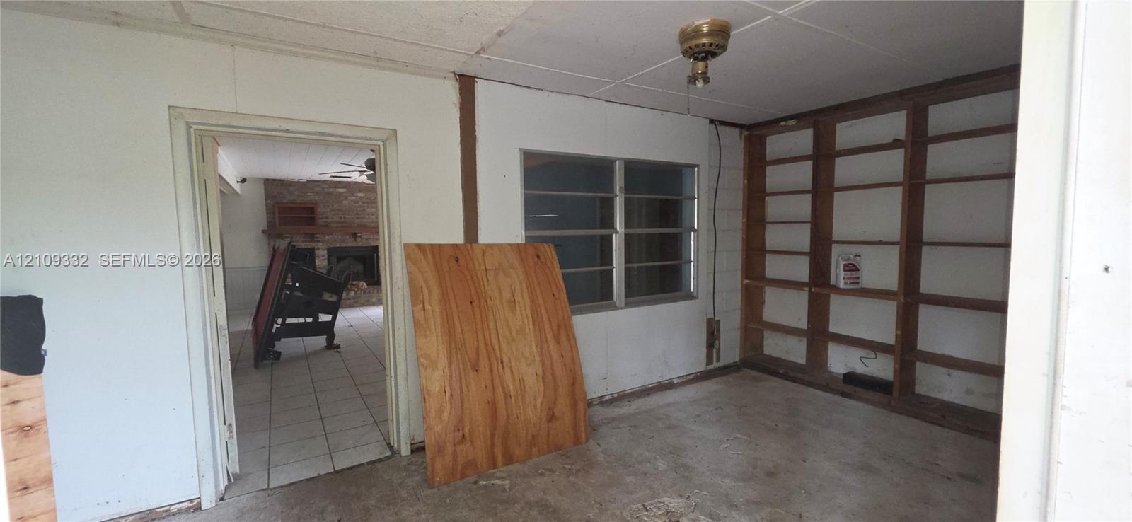 Interior room featuring paneled walls, built-in wooden shelving, metal-frame windows, and a ceiling-mounted light fixture