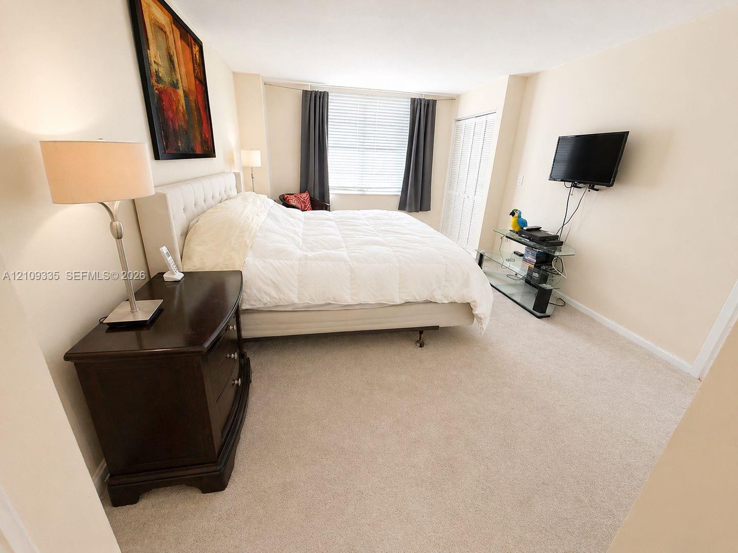 Neutral carpeting, multi-panel closet doors, and a window with horizontal blinds Neutral carpeting, multi-panel closet doors, and a window with horizontal blinds
