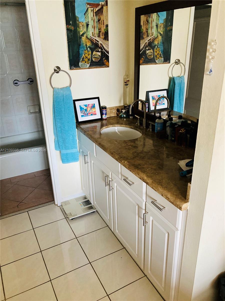 White cabinetry with brushed nickel hardware, stone-finish countertop, undermount sink, and large wall mirror White cabinetry with brushed nickel hardware, stone-finish countertop, undermount sink, and large wall mirror