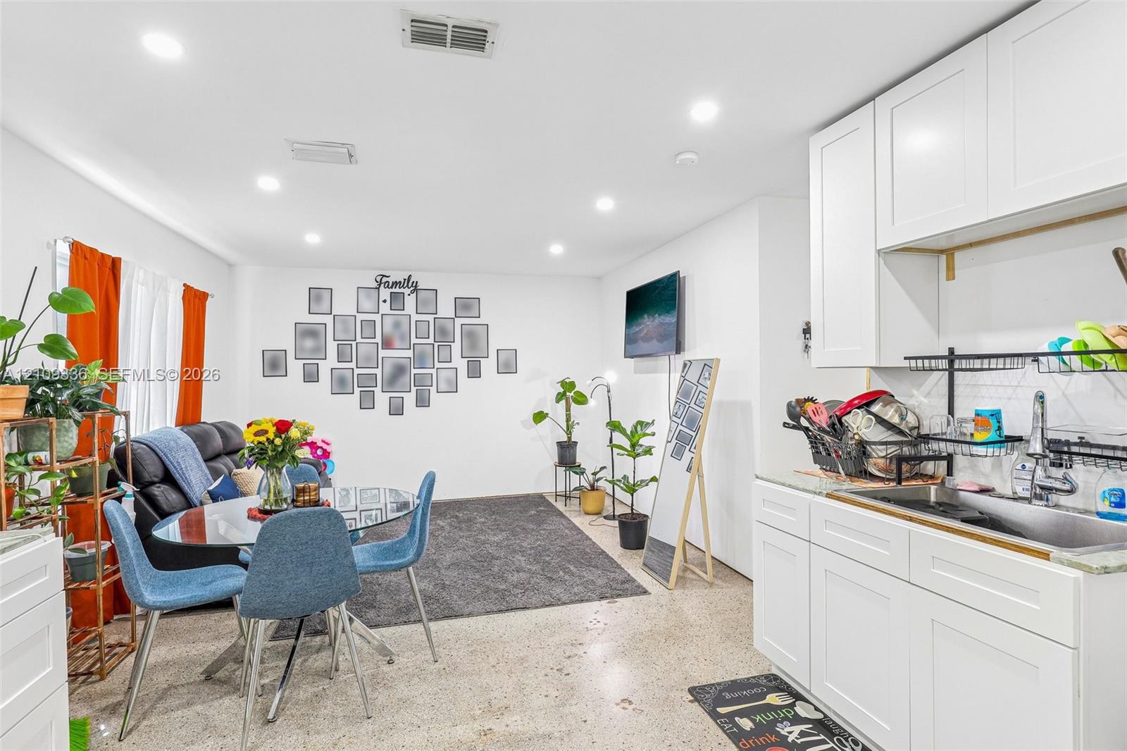 Open-concept space featuring recessed lighting, white shaker-style cabinetry, a stainless steel sink, and polished concrete flooring