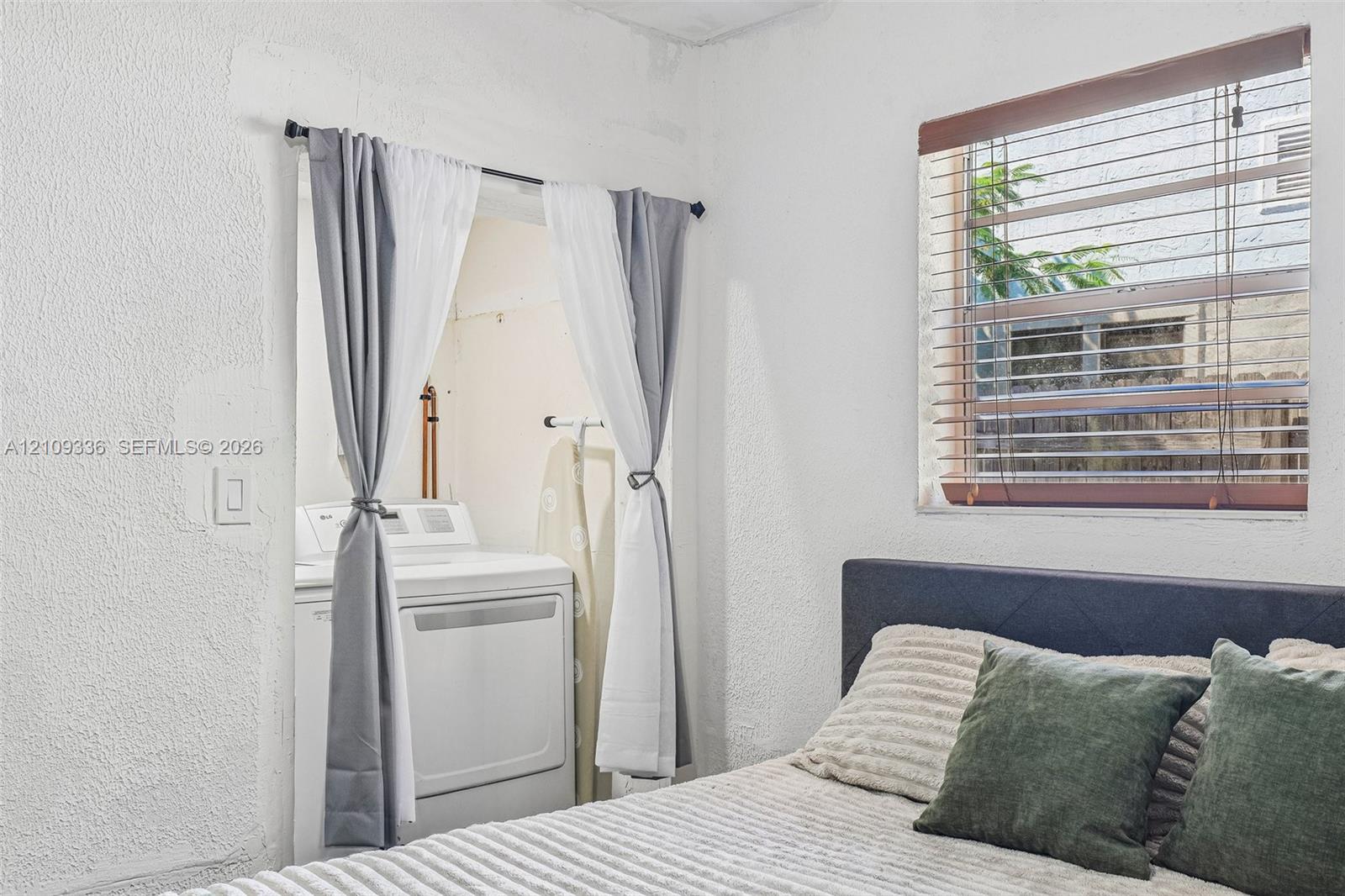 Textured walls and a recessed alcove featuring an integrated laundry hookup with washer