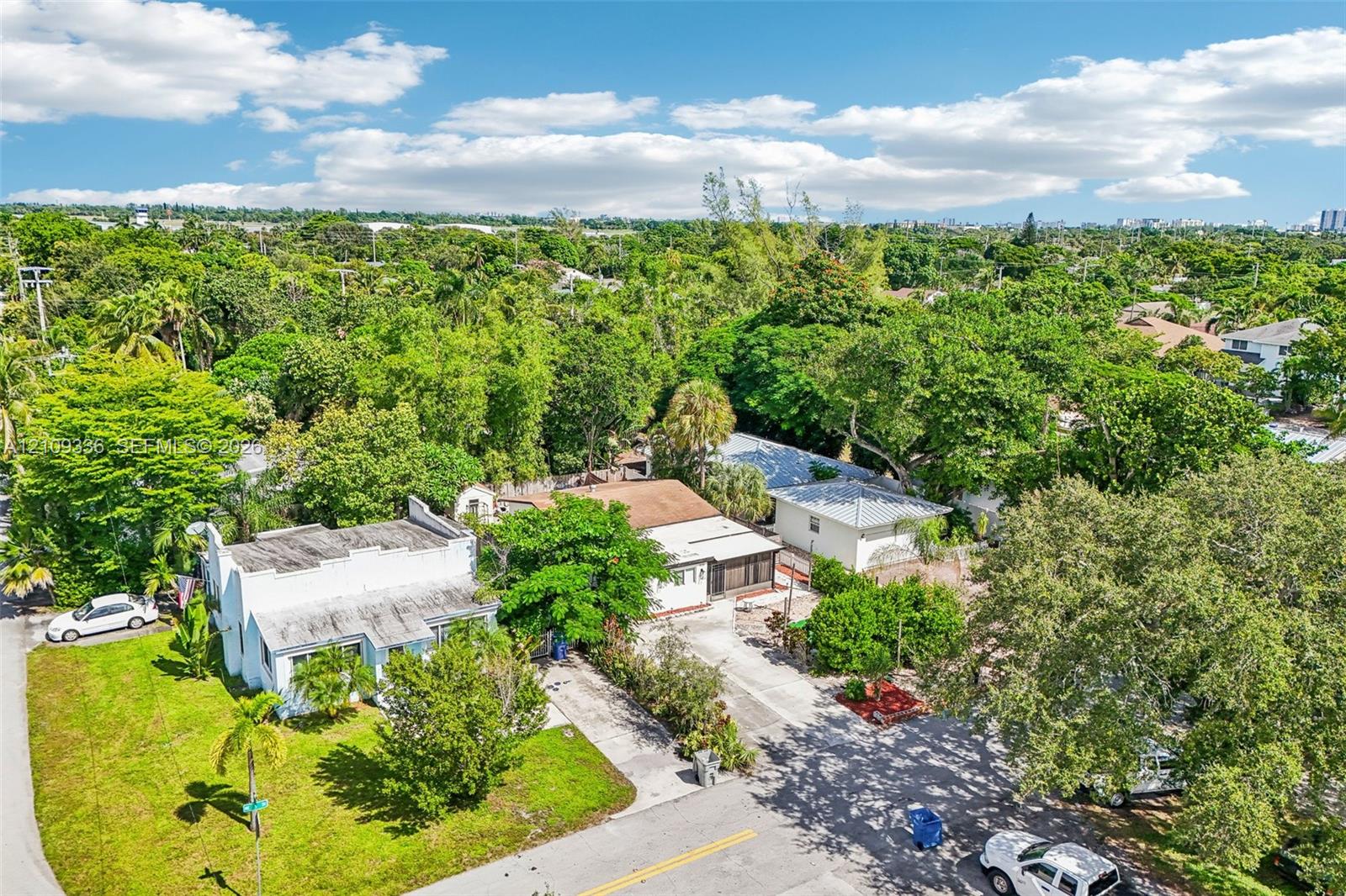 Aerial perspective of property featuring multiple structures, paved driveways, and expansive mature landscaping