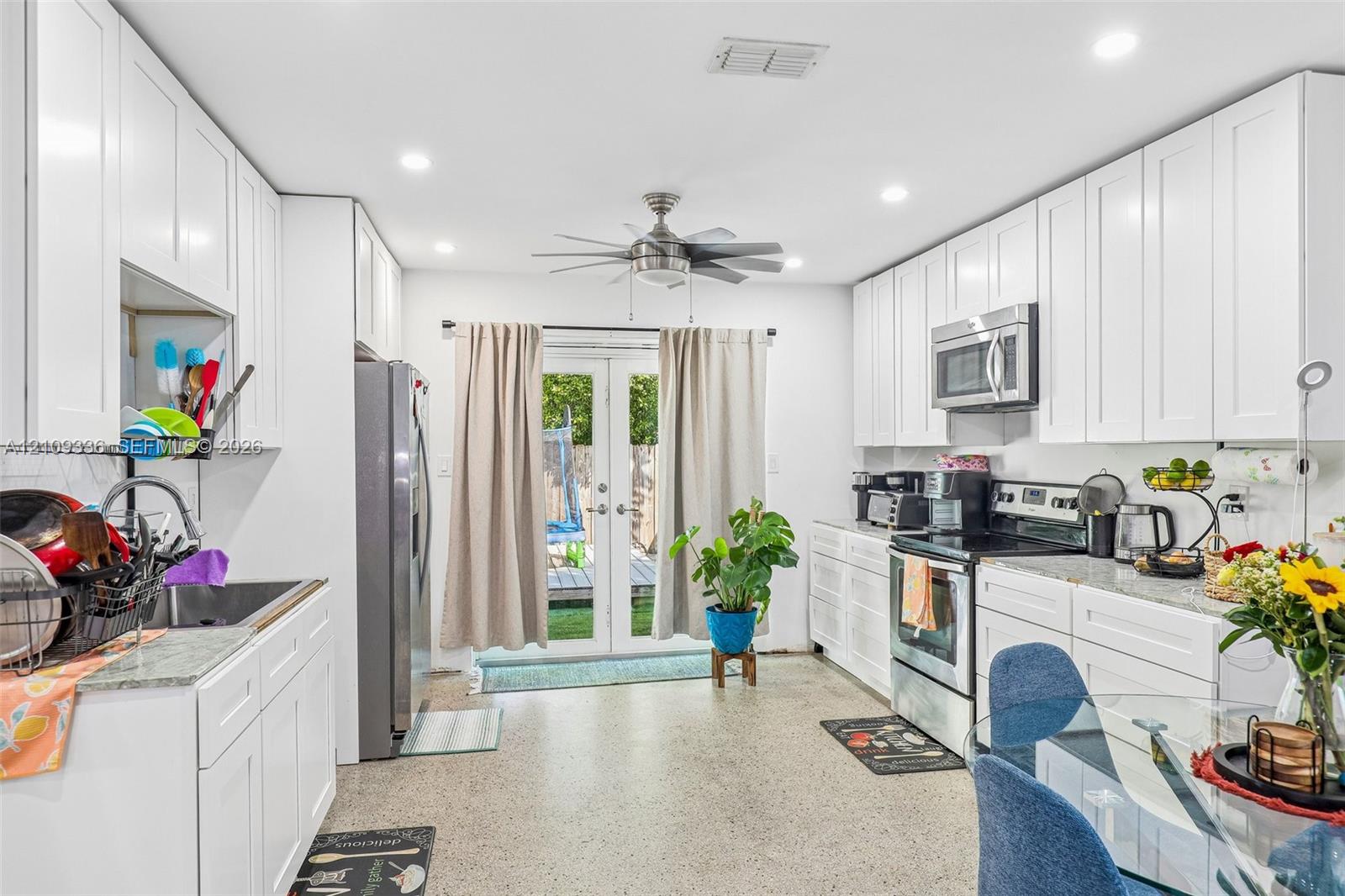 Kitchen featuring white shaker-style cabinetry, stone-finish countertops, stainless steel appliances, recessed lighting, and double glass-paned doors