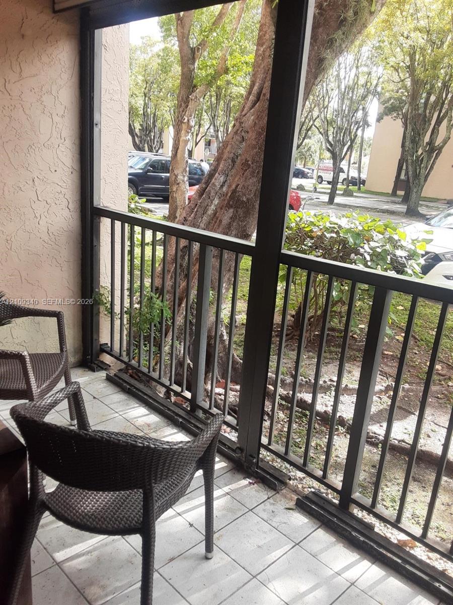 Screen-enclosed balcony with ceramic tile flooring and metal railing