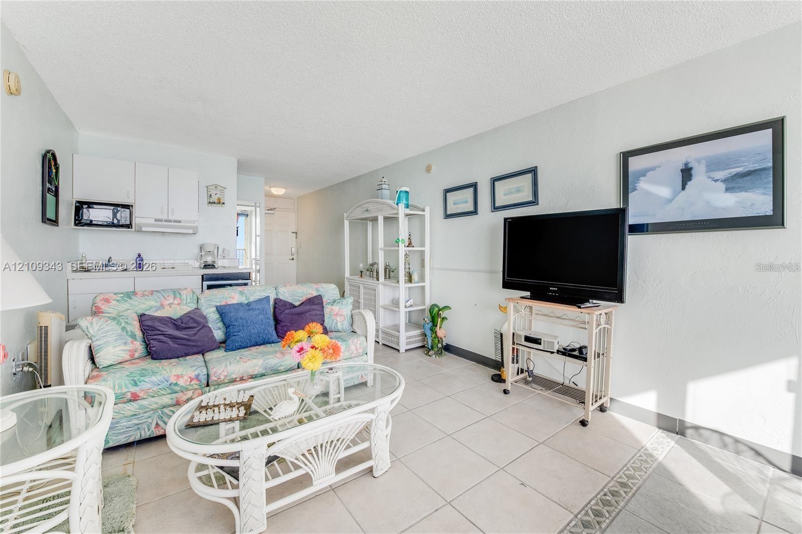Open-concept living space featuring large-format tile flooring, white cabinetry, and a mounted over-the-range microwave