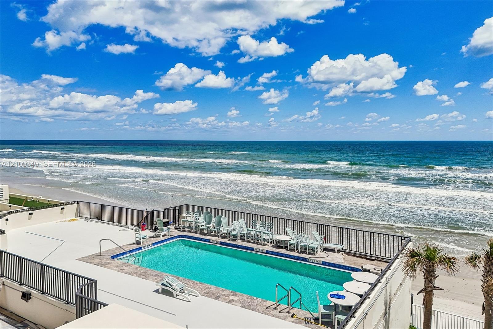 Elevated swimming pool featuring a tile surround, metal perimeter railing, and oceanfront placement