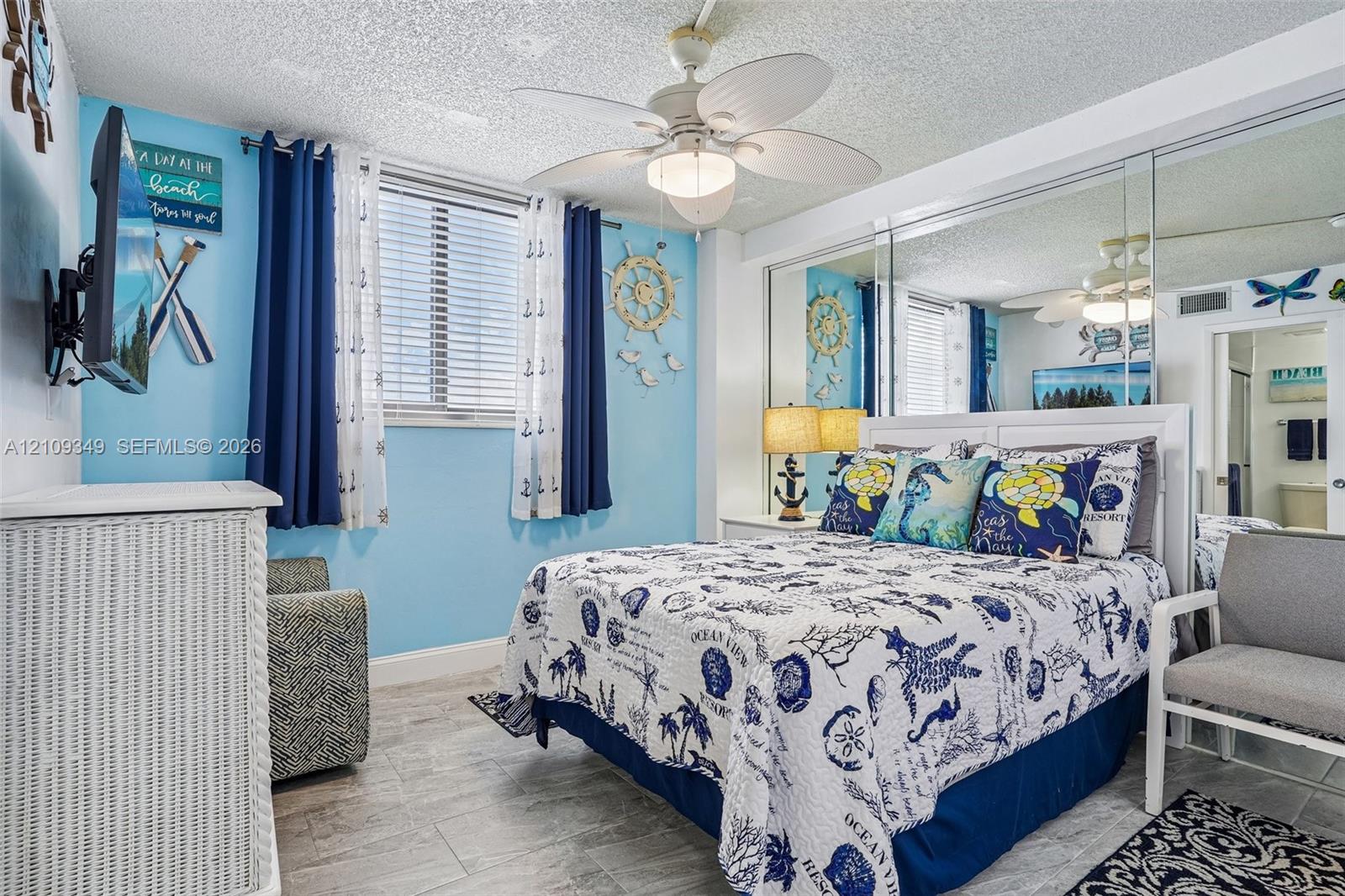 Bedroom featuring tile flooring, ceiling fan with integrated lighting, and wall-to-wall mirrored closet doors
