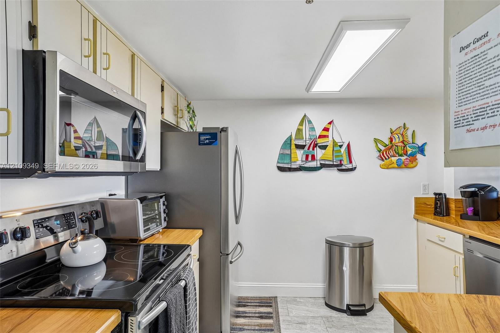 Kitchen featuring stainless steel appliances, butcher block countertops, white cabinetry, and flush-mount LED lighting