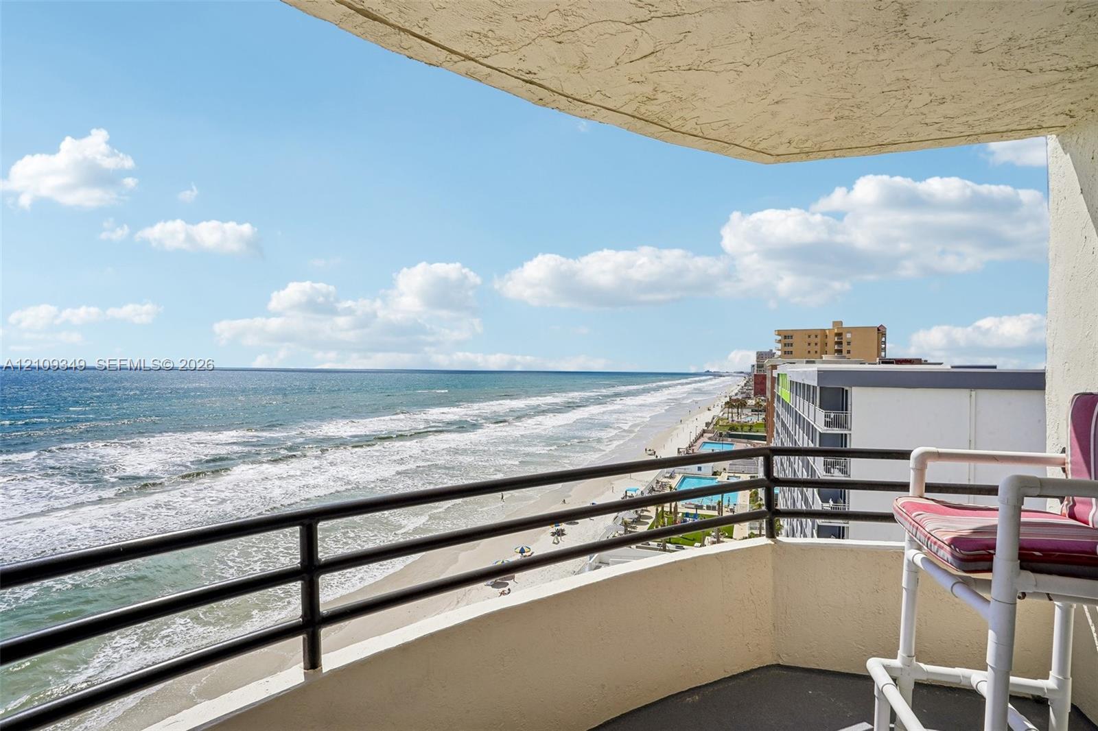 Covered balcony featuring concrete flooring, a solid concrete railing, and a black metal handrail with horizontal bars