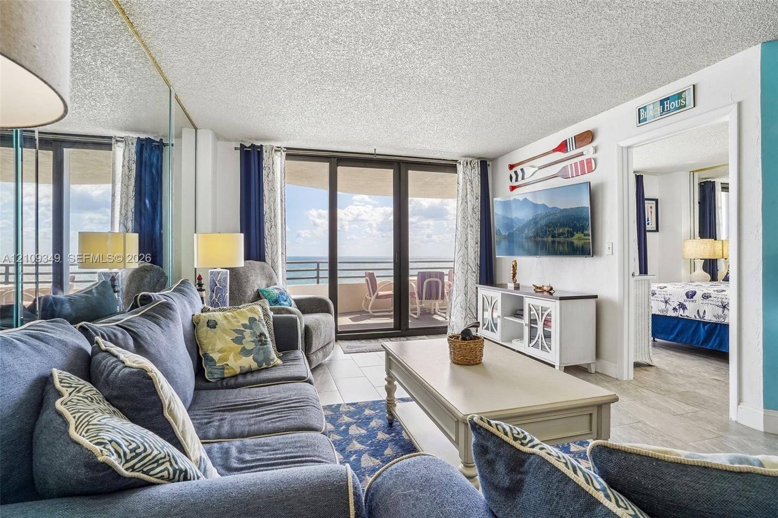 Living area featuring tile flooring, floor-to-ceiling mirrored wall panels, and sliding glass doors with access to an exterior balcony