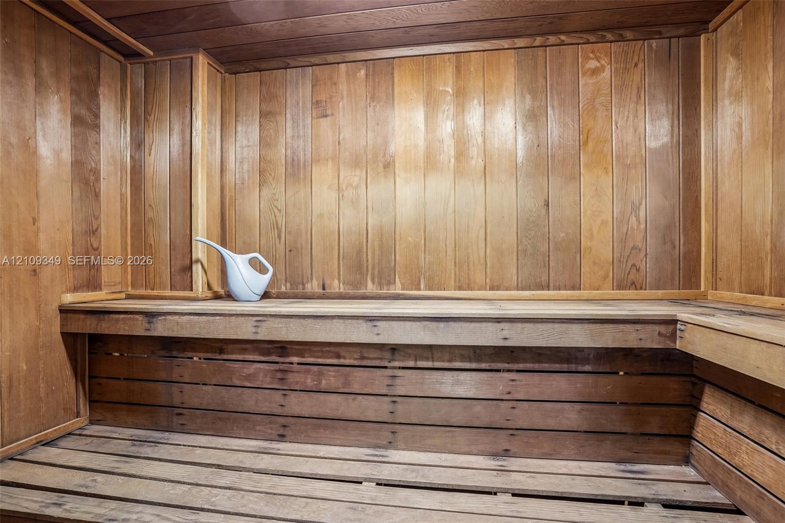 Sauna featuring wood-paneled walls, ceiling, and slatted wood bench seating