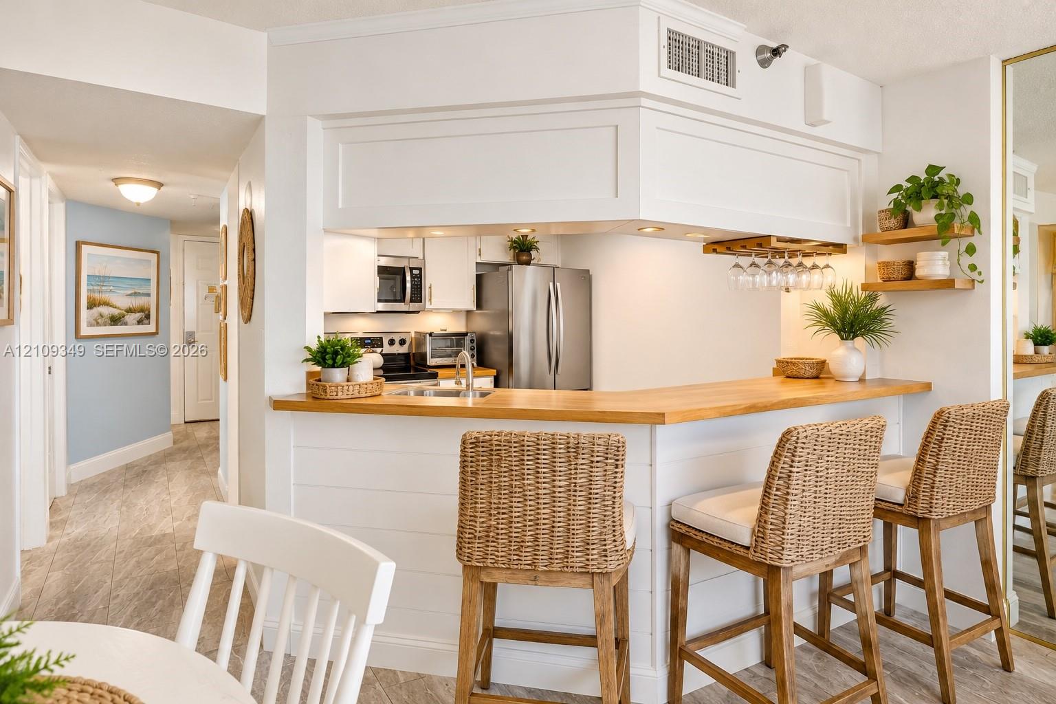 Kitchen featuring white cabinetry, wood-finish breakfast bar counter, recessed lighting, and built-in stemware storage