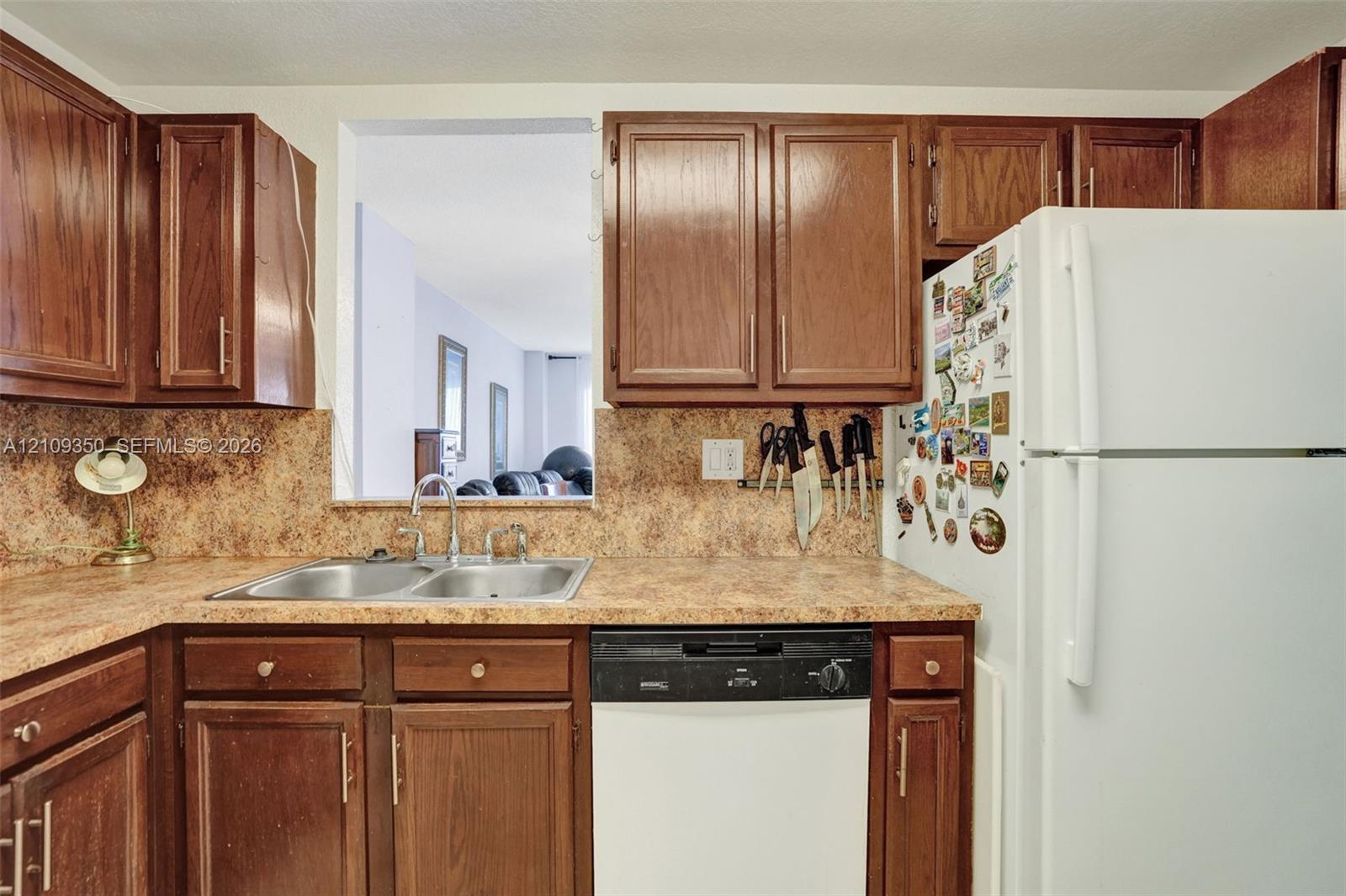 Kitchen featuring stained-wood cabinetry, laminate countertops, a dual-basin stainless steel sink, and integrated dishwasher