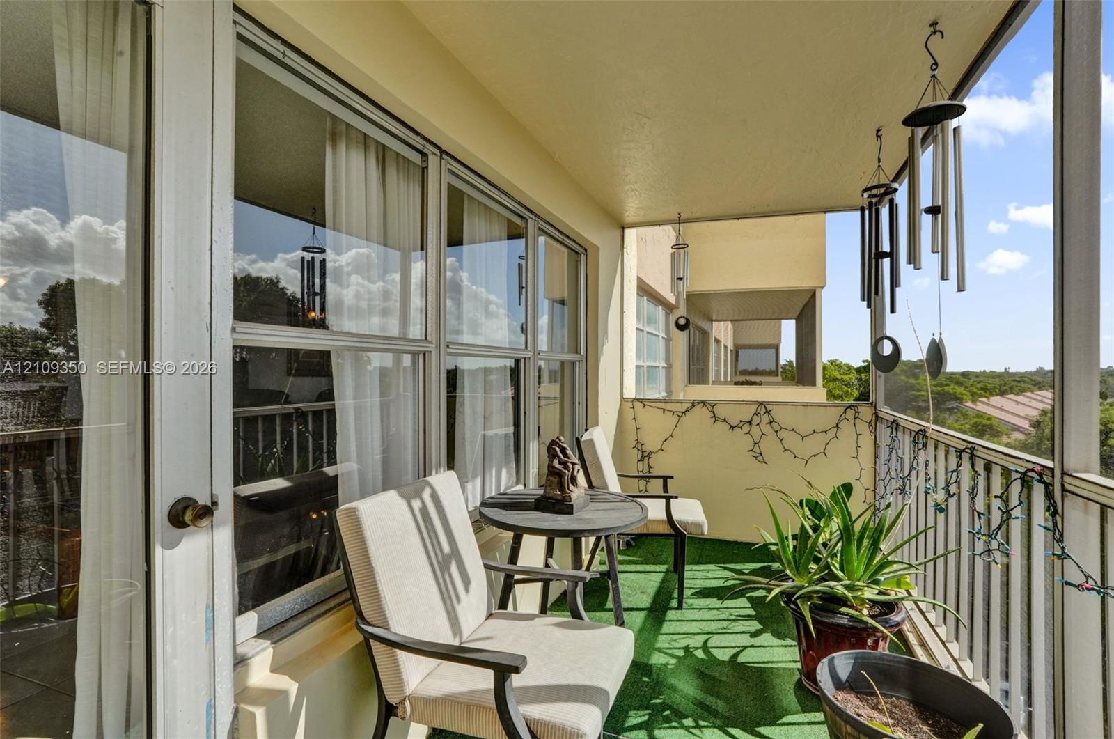 Covered balcony featuring green floor covering, metal railings, and large sliding glass door access
