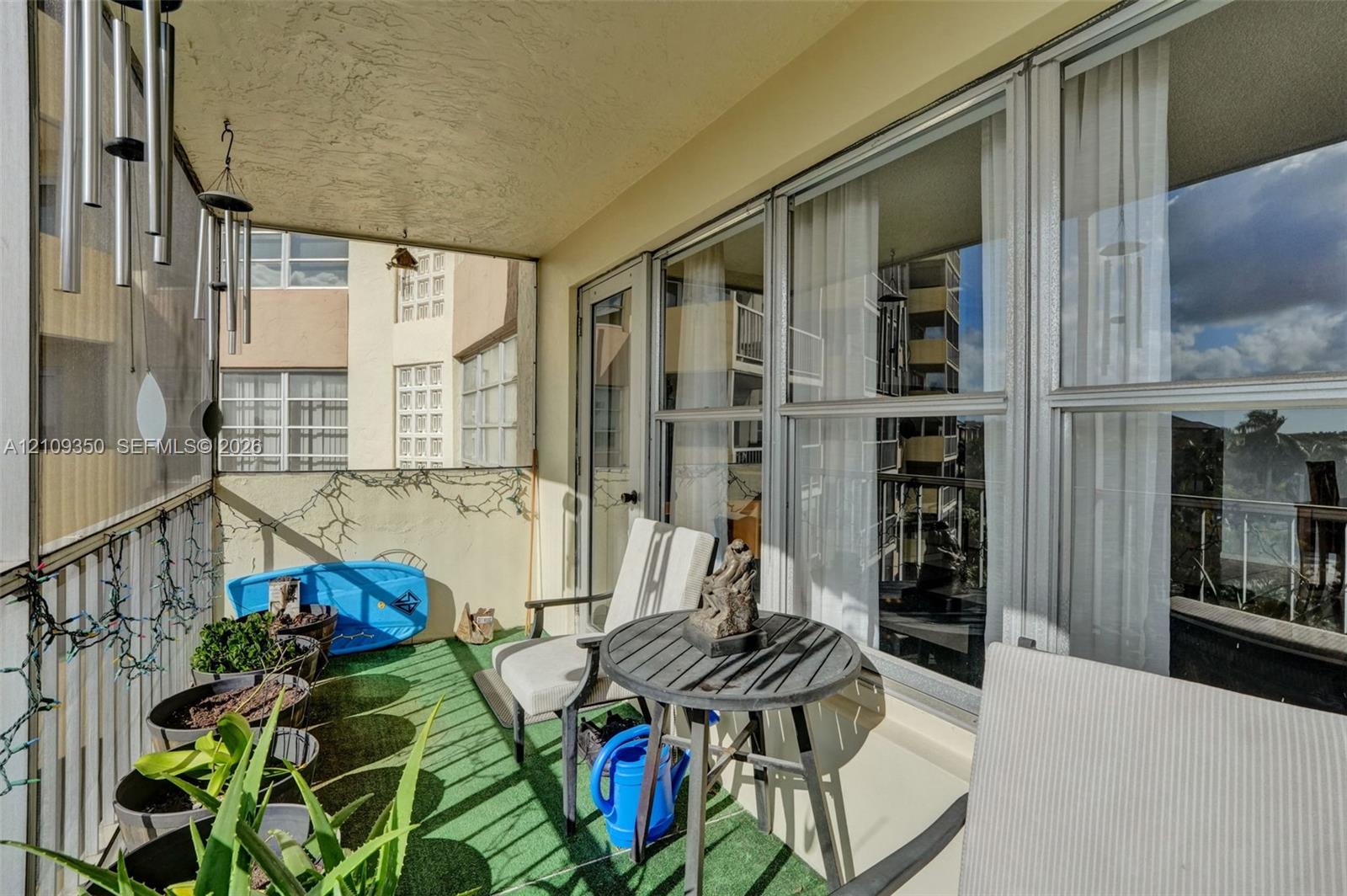 Covered balcony featuring metal railing, large floor-to-ceiling windows, and artificial turf flooring
