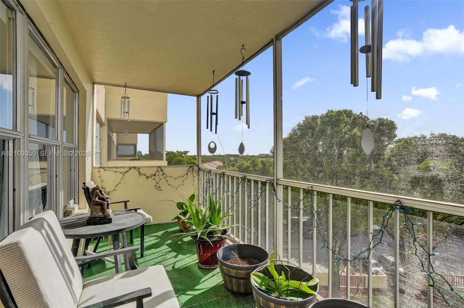 Screened-in balcony featuring metal railing, overhead lighting, and solid wall construction