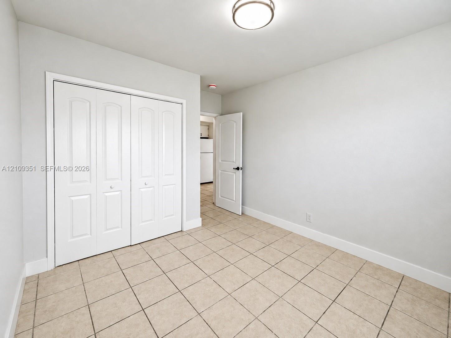 Interior room featuring neutral-toned tile flooring, recessed ceiling lighting, and a bi-fold door closet
