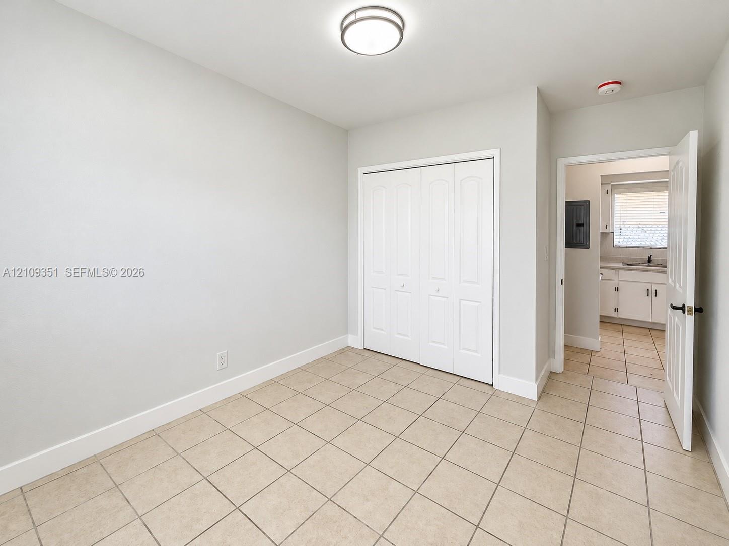 Room featuring ceramic tile flooring, neutral wall paint, and a built-in closet with paneled double doors