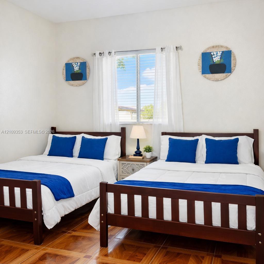 Neutral interior room featuring wood-finish flooring, a double-hung window, and white wall finishes