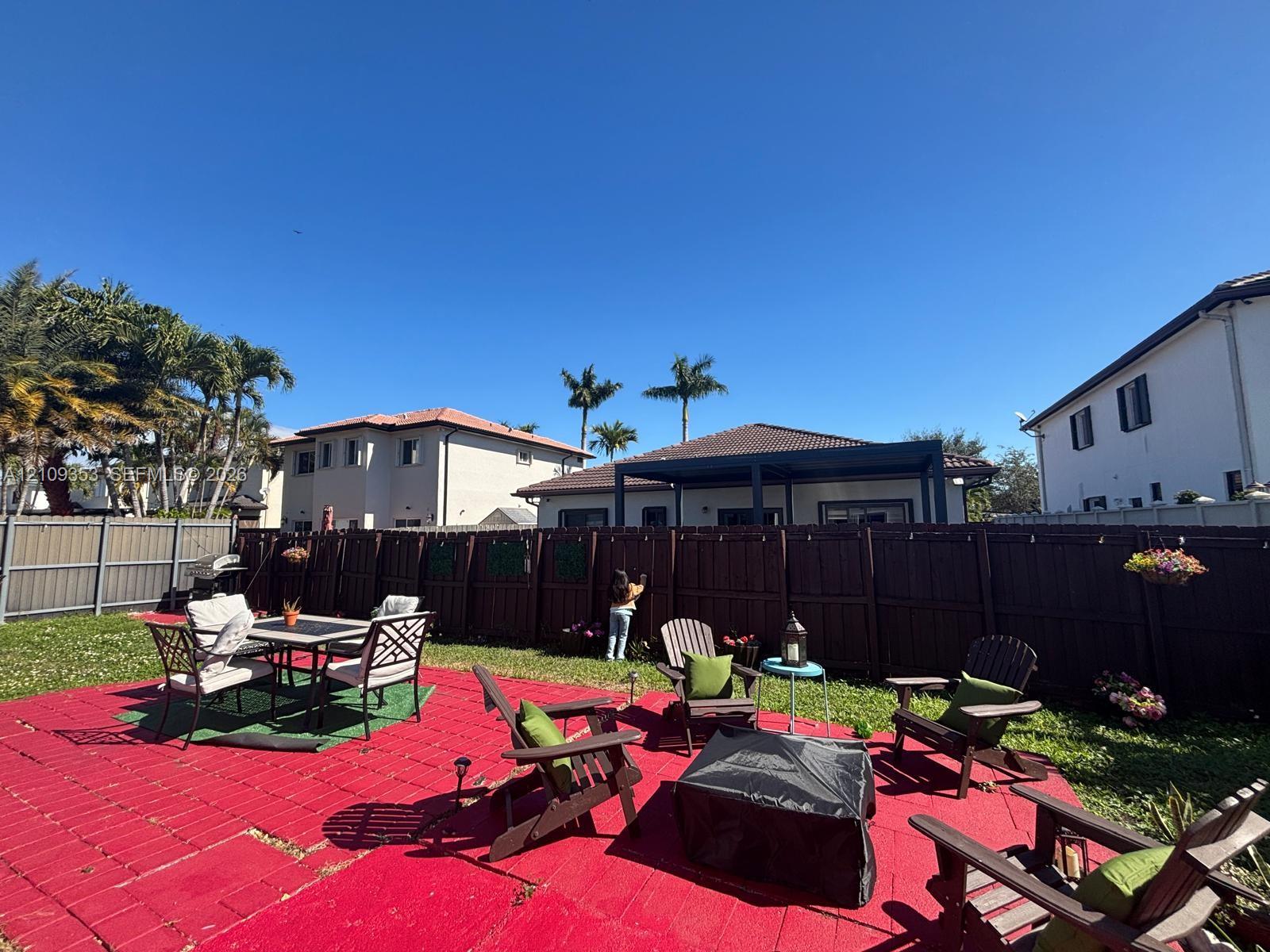 Backyard featuring a red paver patio, dark-toned wood privacy fencing, and a covered rear porch