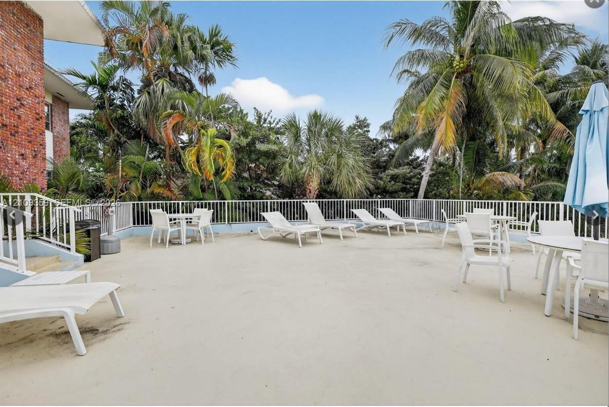 Expansive concrete deck featuring metal perimeter railings and mature palm trees