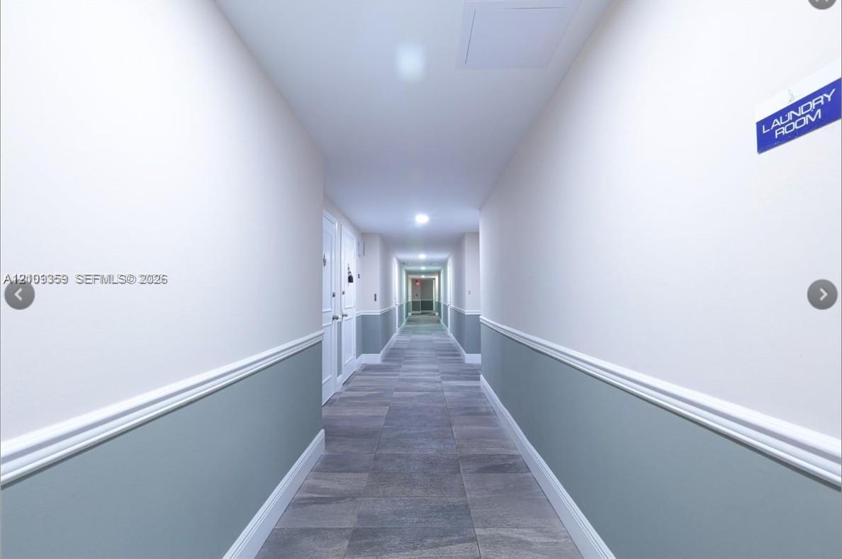 Hallway featuring grey tile flooring, two-tone wall paint, white chair rail molding, and recessed ceiling lighting