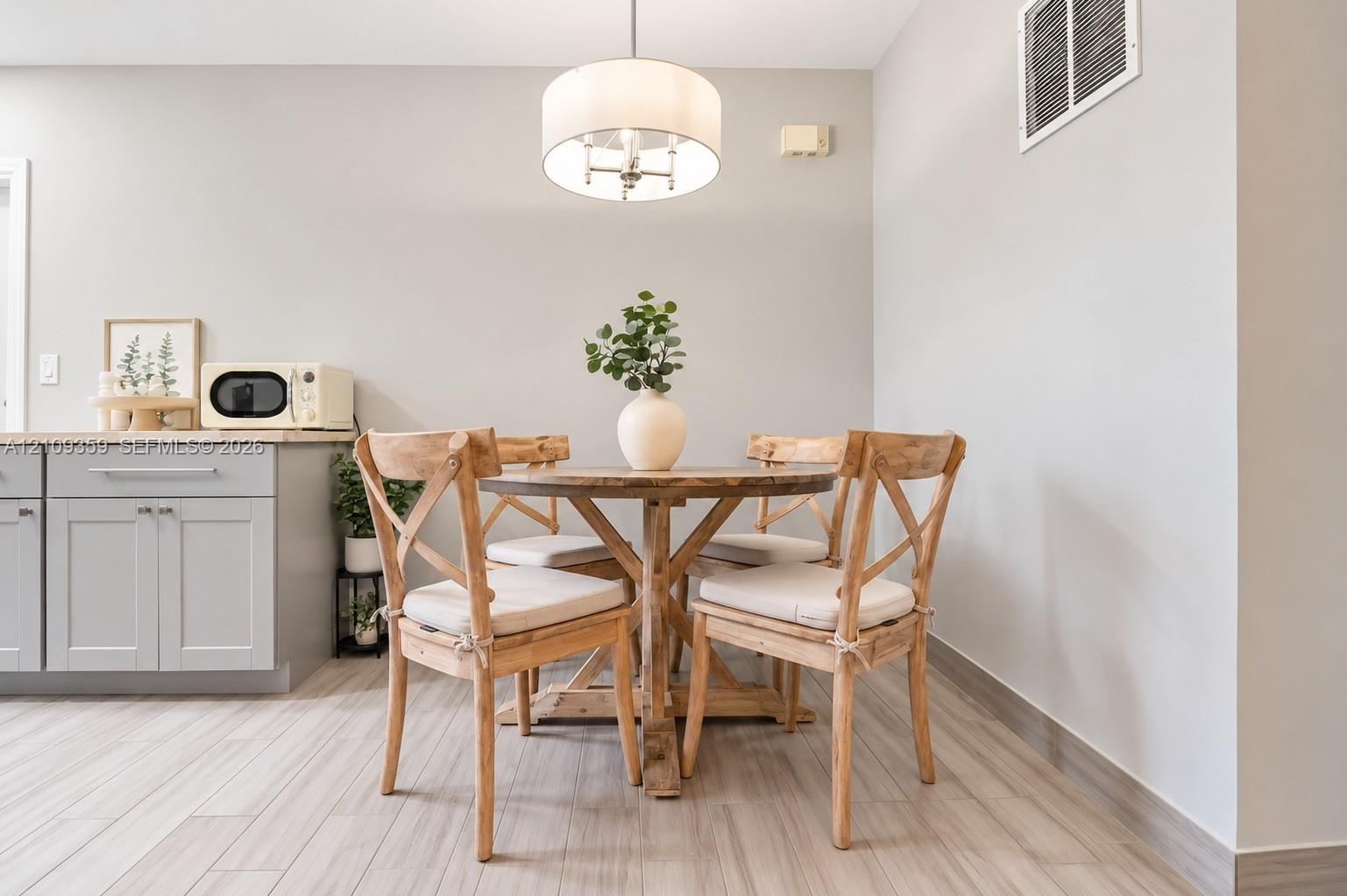 Light gray cabinetry with stone-finish countertops, tile flooring, and a drum-style pendant light fixture Light gray cabinetry with stone-finish countertops, tile flooring, and a drum-style pendant light fixture