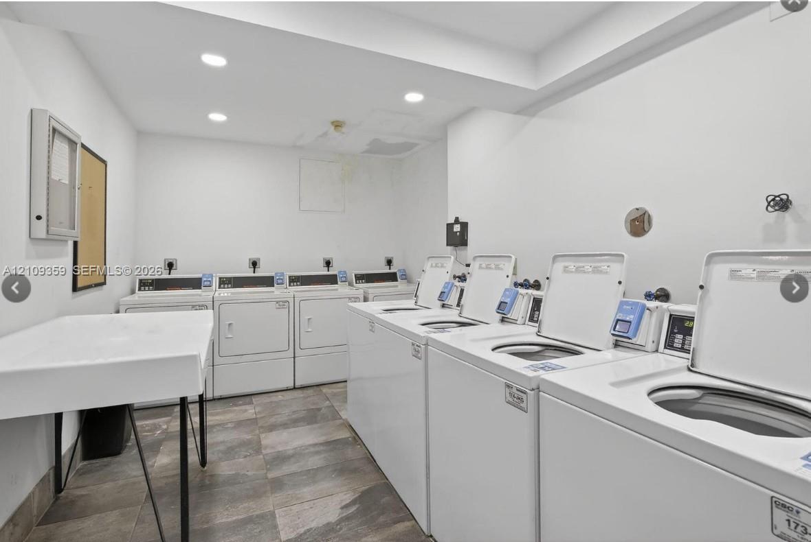 Laundry facility featuring multiple commercial-grade top-load washers and dryers, tile flooring, recessed lighting, and a built-in utility sink