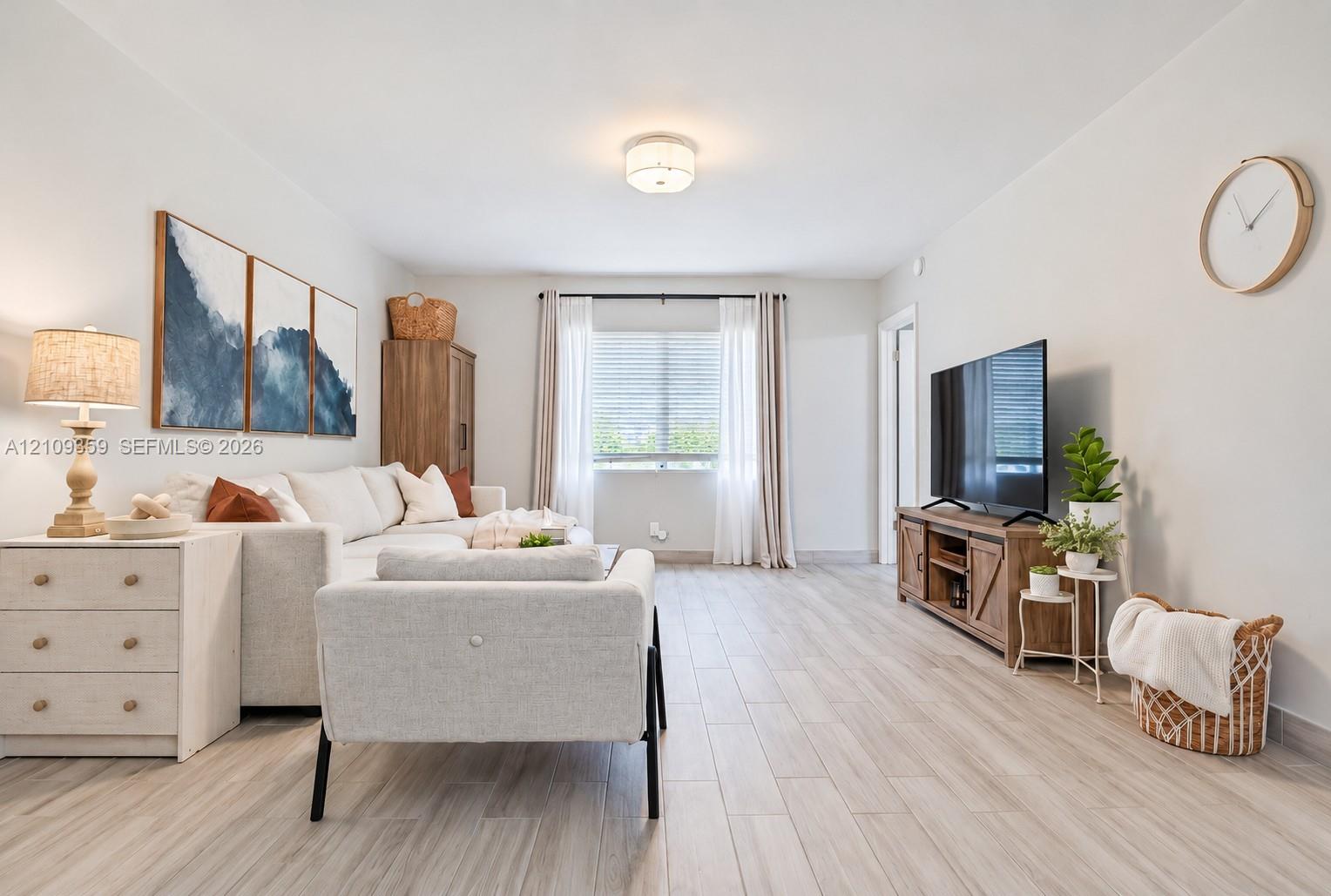 Neutral interior space featuring wood-finish flooring, a single-window configuration with horizontal blinds, and a flush-mount circular ceiling light fixture Neutral interior space featuring wood-finish flooring, a single-window configuration with horizontal blinds, and a flush-mount circular ceiling light fixture