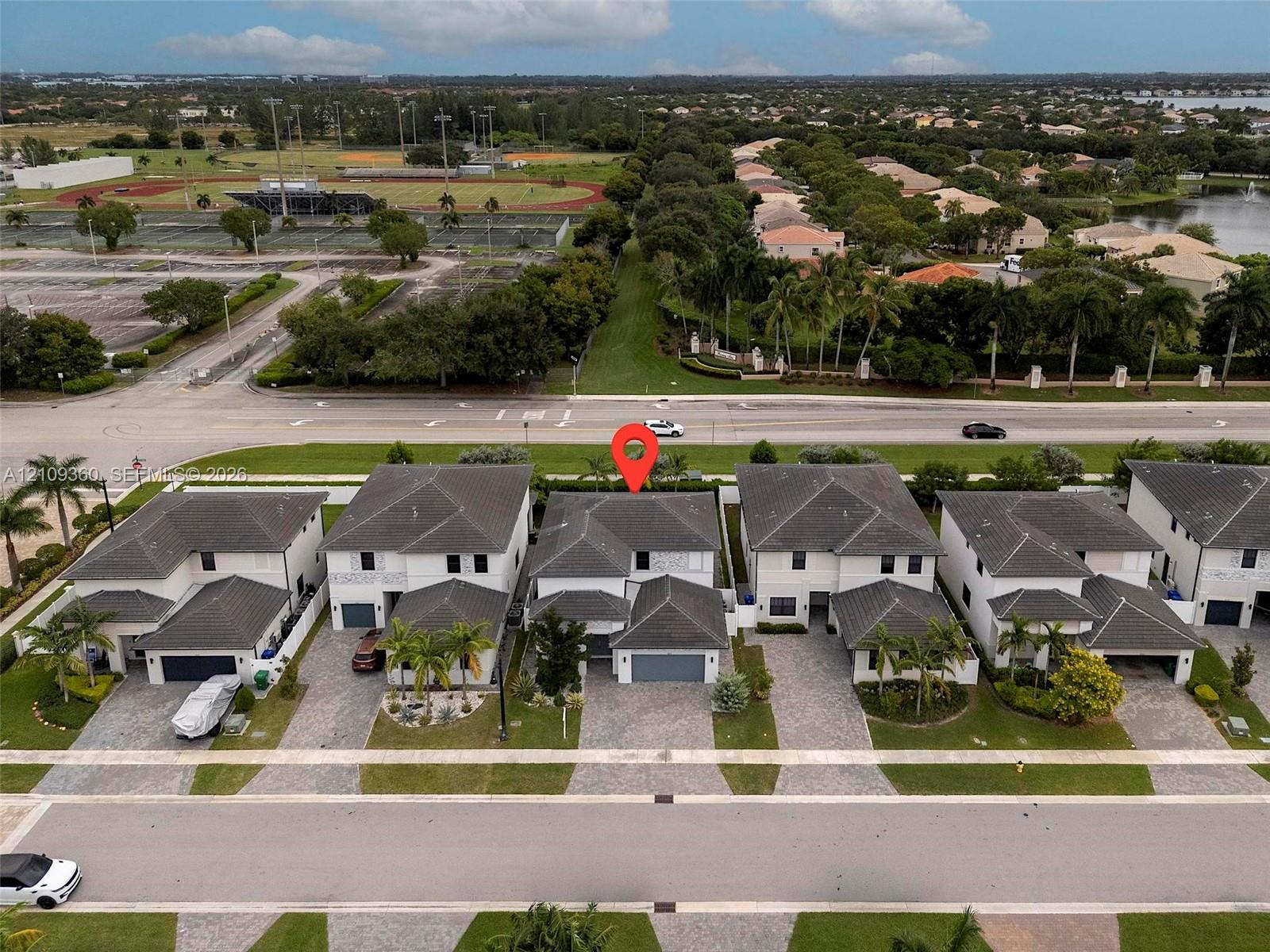 Aerial perspective of a two-story residence featuring a hip roof design, paver driveway, and an attached two-car garage