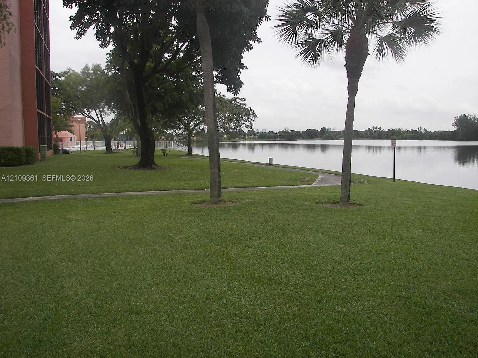 Waterfront grounds featuring mature trees, palm trees, expansive lawn space, and concrete walkways Waterfront grounds featuring mature trees, palm trees, expansive lawn space, and concrete walkways