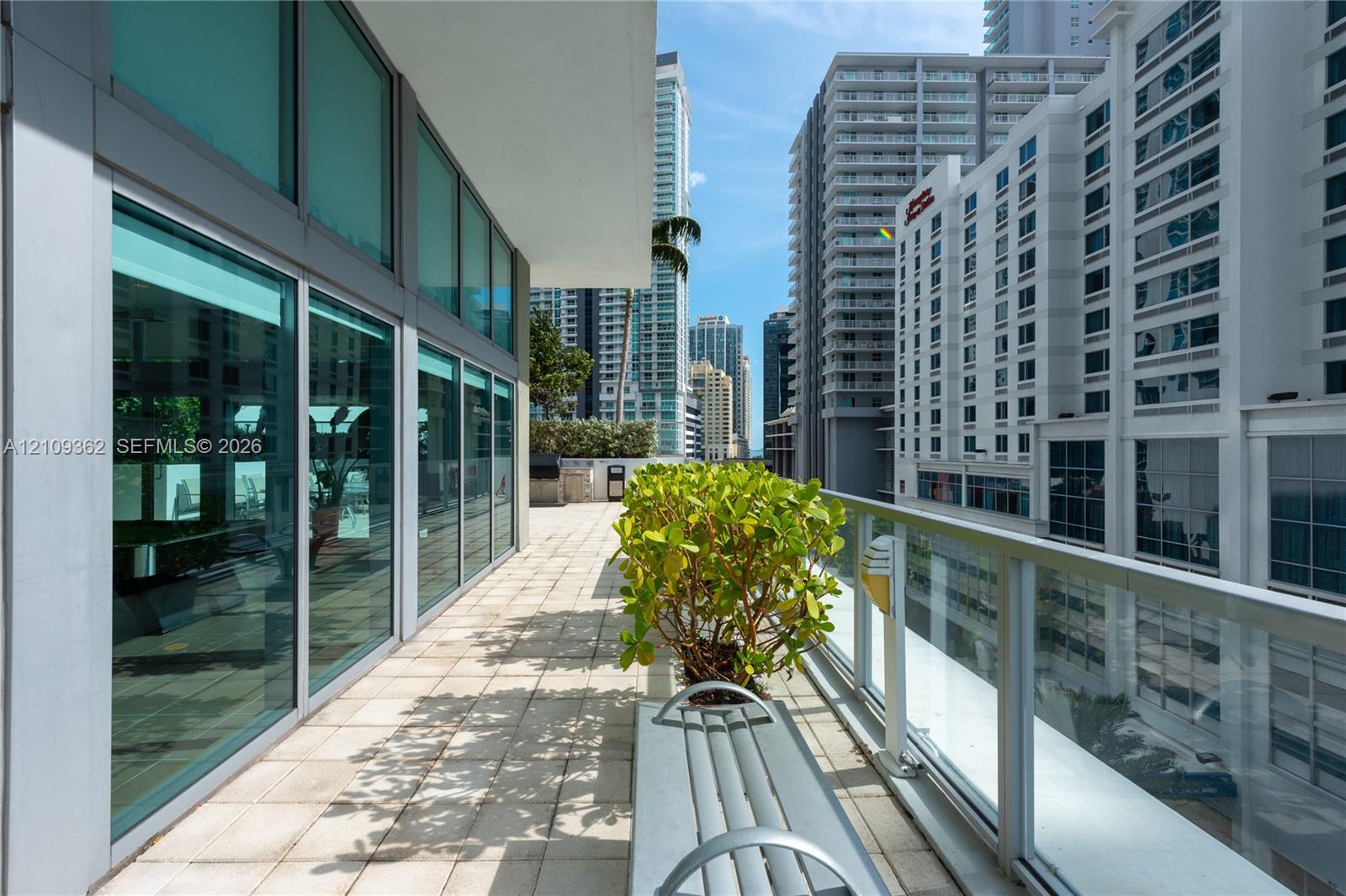 Expansive balcony featuring floor-to-ceiling glass paneling, tile flooring, and a glass-paneled railing