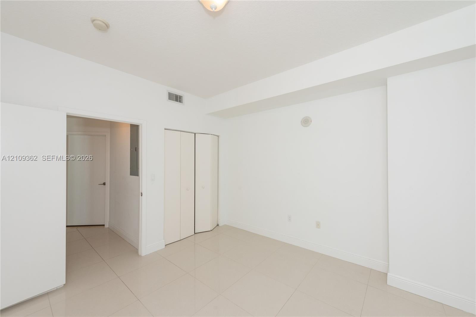 Neutral interior featuring tile flooring, smooth ceiling, and built-in closet with double-panel doors