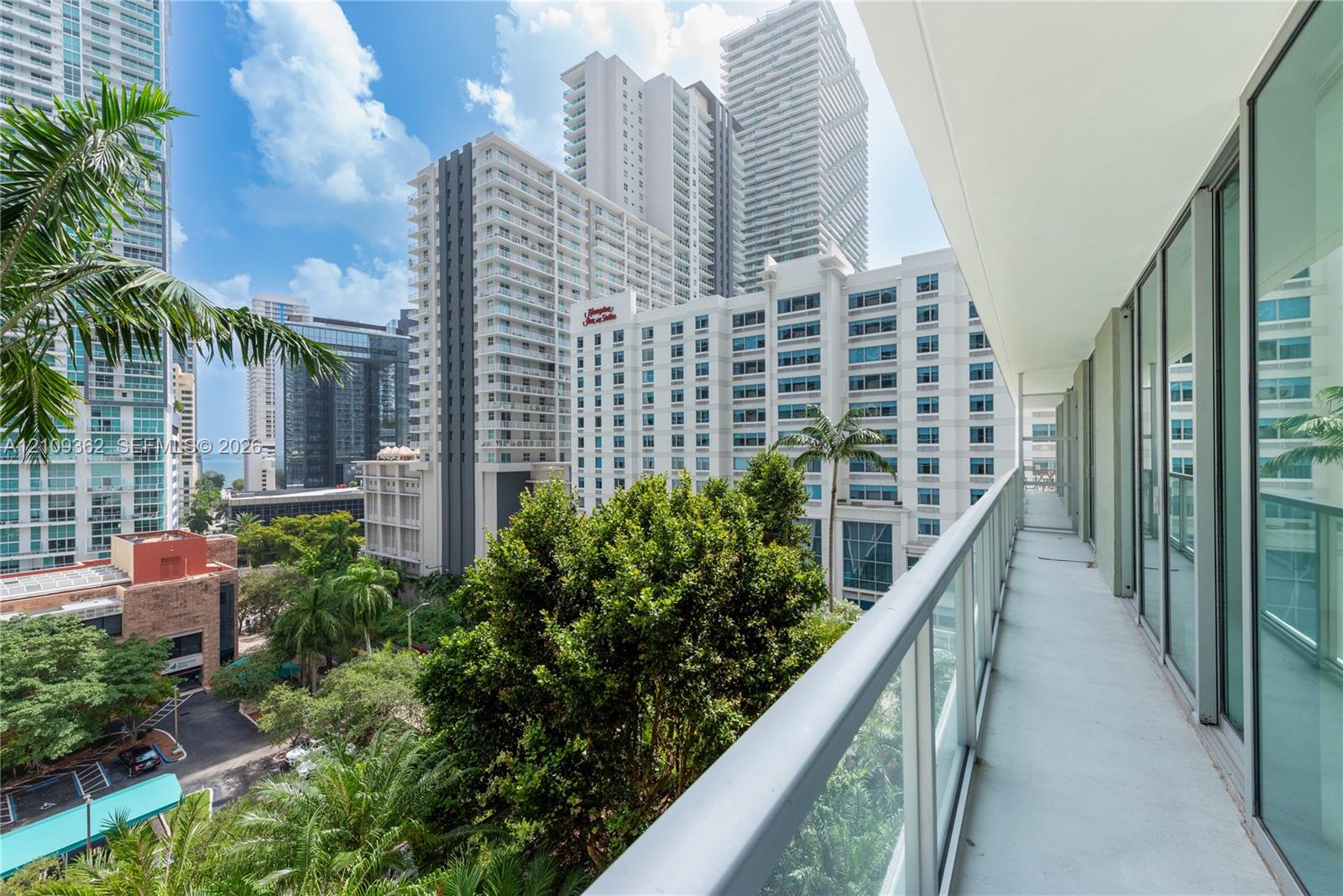 Covered balcony featuring glass paneled railings, floor-to-ceiling windows, and concrete flooring