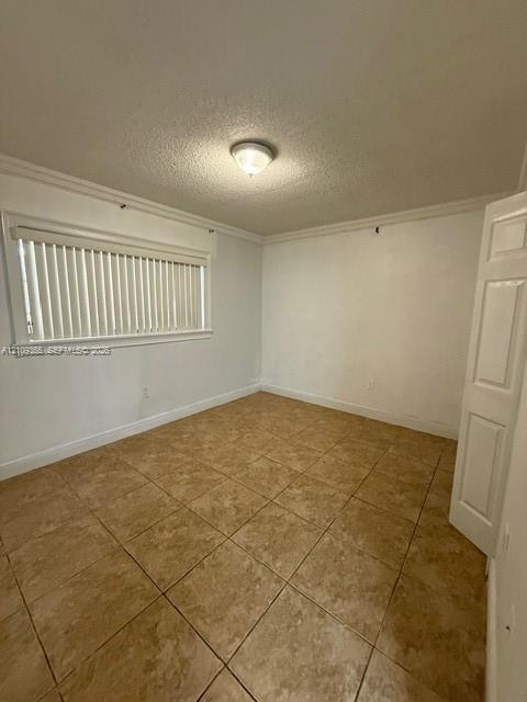 Room featuring neutral-toned tile flooring, crown molding, a flush-mount ceiling light fixture, and horizontal window blinds Room featuring neutral-toned tile flooring, crown molding, a flush-mount ceiling light fixture, and horizontal window blinds