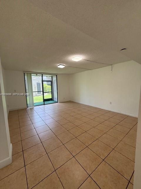 Neutral-toned ceramic tile flooring, ceiling-mounted light fixtures, and a sliding glass door providing access to a screened-in outdoor area Neutral-toned ceramic tile flooring, ceiling-mounted light fixtures, and a sliding glass door providing access to a screened-in outdoor area
