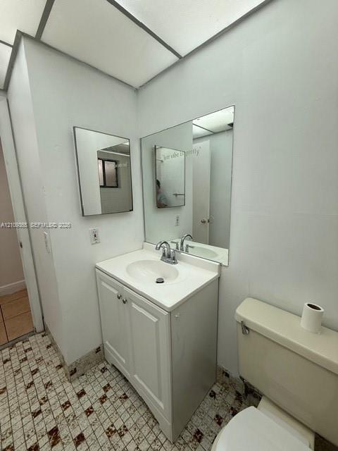 Bathroom vanity featuring a white cabinet base, integrated sink, and dual-handle chrome faucet, complemented by a large wall-mounted mirror and patterned tile flooring Bathroom vanity featuring a white cabinet base, integrated sink, and dual-handle chrome faucet, complemented by a large wall-mounted mirror and patterned tile flooring