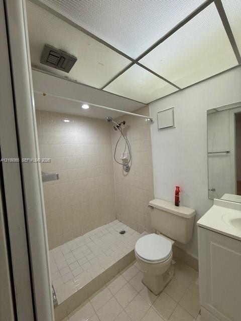 Bathroom featuring a walk-in shower with tile surround, drop-in sink, vanity cabinet, and recessed ceiling panel lighting
